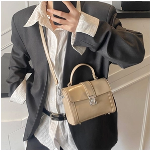 Polished beige leather crossbody bag with silver buckle worn by a model in black suit