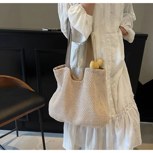 Detail of woven straw tote bag with brown leather handles and decorative tulips