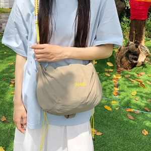 Detail showing embroidered beaut letters and yellow drawstring on khaki nylon crossbody bag
