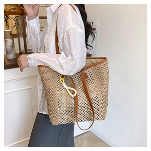 Detail of woven straw tote bag with brown leather straps and colorful tassel accessory