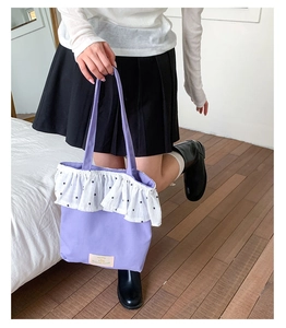 Detail of lavender canvas tote bag with floral ruffled trim and woven brand label