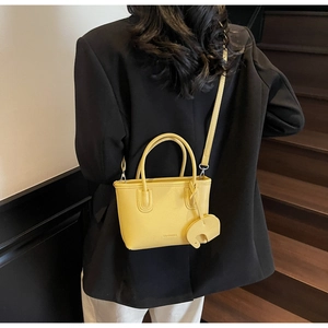 Detail of yellow lychee texture bucket bag with cute elephant charm on a model