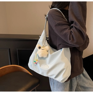 Detail of light blue checkered canvas shoulder bag with a cute plush star charm