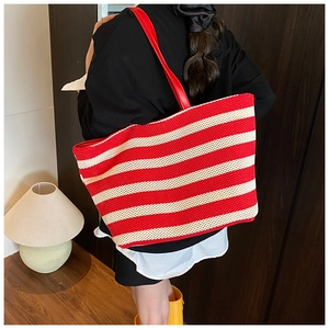Dettaglio della borsa tote intrecciata a righe rosse e bianche con tracolla in pelle rossa