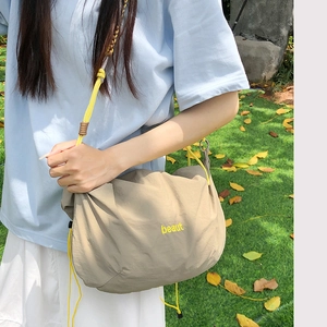Detail of nylon crossbody bag with yellow drawstring strap and beaut printed logo