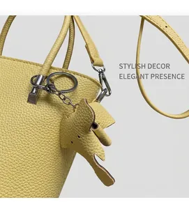 Detail of yellow litchi grain leather bucket bag with cute elephant charm and silver hardware