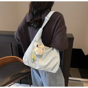 Detail of light blue checkered canvas hobo bag with cute plush rabbit charm