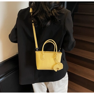 Detail of yellow lychee texture handbag with cute elephant charm and adjustable strap