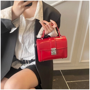 Detailed mirror selfie of a red leather square bag with silver clasp and top handle