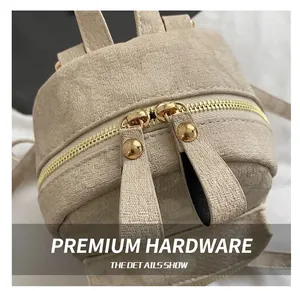 Close-up of beige textured fabric backpack with premium golden double zippers and rivets