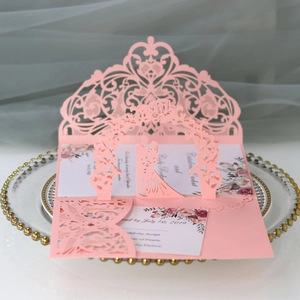 Macro detail of laser-cut pink wedding invitation set with 3D pop-up couple and floral card