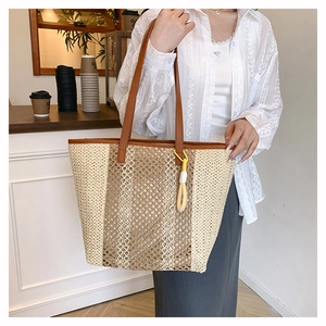 Detail shot of large woven beach tote with brown leather handles and decorative tassel