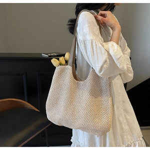 Detail of woven tote bag with brown leather strap and decorative tulip inside