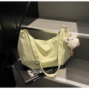 Dettaglio della borsa hobo trapuntata verde chiaro con ciondolo a orsetto su sfondo urbano