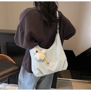 Detail of light blue checkered canvas tote bag with a plush bunny charm on shoulder