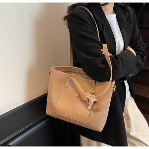 Detail view of lychee leather tote bag with decorative horse charm and gold hardware
