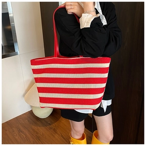 Vista dettagliata della borsa tote intrecciata a righe rosse e bianche con manici