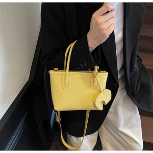 Detail of yellow lychee texture leather tote with an elephant charm and embossed logo
