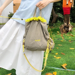 Detail of waterproof nylon drawstring crossbody bag with neon yellow accents and embroidery