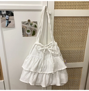 Detail of white tiered ruffle shoulder bag with delicate bow and textured fabric