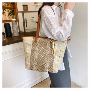 Detail of woven straw tote bag with brown leather straps and decorative tassel