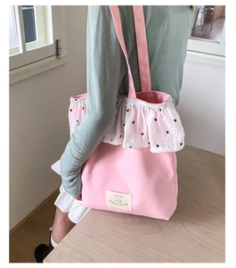 Detail of pink canvas tote bag featuring floral ruffles and a decorative woven label