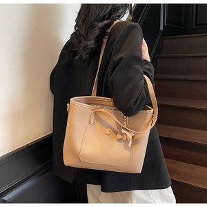 Detail view of apricot lychee pattern leather tote bag with a bow charm and side pocket