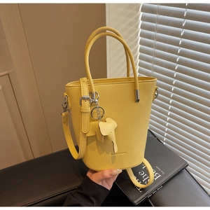 Macro detail of yellow bucket bag featuring lychee texture leather and elephant charm