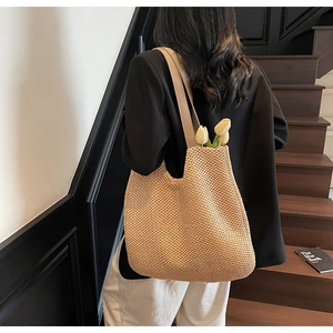 Close-up of woven straw tote bag with brown leather straps and tulip flower detail