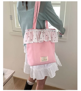 Detail of pink canvas tote bag featuring floral lace trim and vintage woven label