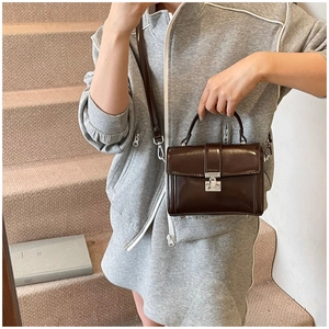 Detail of glossy chocolate brown patent leather bag with silver metallic twist lock