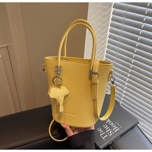 Detail of yellow lychee pattern leather bucket bag with cute elephant charm and silver hardware