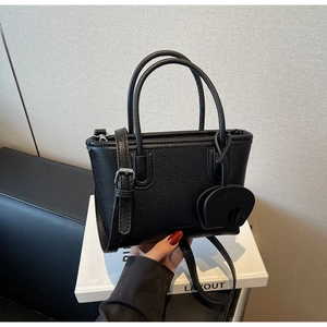 Detail of black lychee grain leather handbag with matching long strap and elephant charm