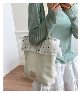 Close-up of cream canvas tote bag with black polka dot lace ruffles and vintage patch