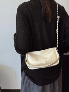Creamy white pillow bag with silver chain strap worn crossbody over a black top