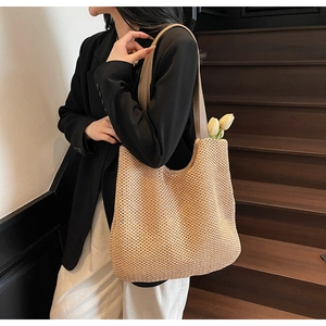 Detail of beige woven tote bag showing fine straw texture and faux leather strap handle