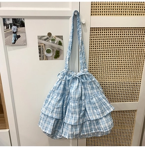Detail of blue gingham tiered tote bag with decorative drawstring bow and soft ruffles