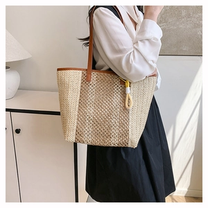 Close-up of large woven beach tote with contrast beige patterns and leather straps
