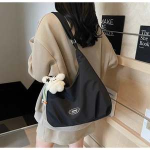 Detail of black canvas hobo bag with adjustable strap and cute white plush rabbit charm