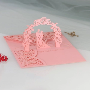 Detailed laser cut 3D pop-up wedding invitation featuring pink floral arch and couple