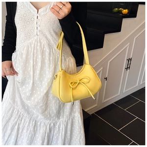 Close-up of vibrant yellow crescent bag featuring lychee texture and bow detail