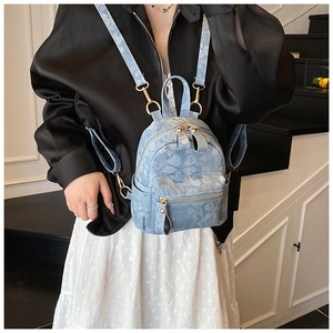Detail of light blue denim mini backpack with floral jacquard and gold metal zippers