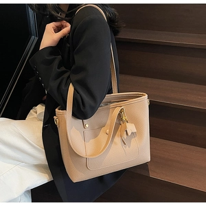Detail of beige pebble leather tote bag with gold hardware and matching leather charm decoration