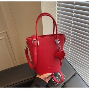Detail of red bucket bag in litchi grain leather with elephant charm and silver hardware
