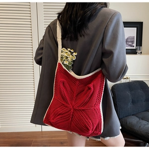 Detail of red crochet tote bag with textured knit pattern and cream trim borders
