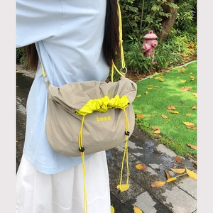 Outdoor shot of khaki nylon crossbody bag with bright yellow drawstring and beaut print