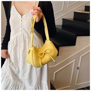 Detail of bright yellow bow hobo bag with pebble leather texture and silver zipper