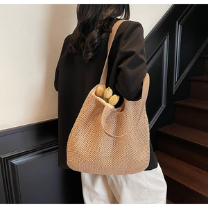 Close-up of woven straw hobo bag with wide shoulder strap and decorative tulips