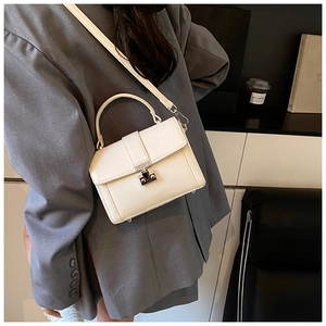 Close-up of a white patent leather crossbody bag with silver hardware on a model