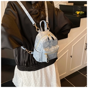 Detail of light blue jacquard mini backpack showing gold hardware and textured fabric